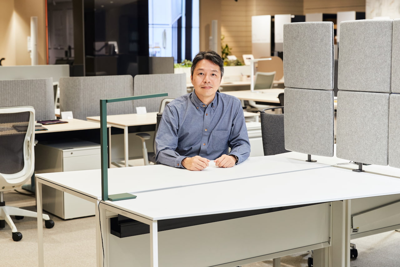 自身がデザインしたオフィスデスク「SOLISTE※5」とともに。パブリックデザイン室の山本崇之